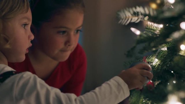 little girls decorating christmas tree with ornaments and baubles enjoying festive celebration at home 4k footage