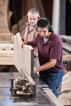 Carpenters Cutting Large Wooden Slab On Table Saw In Workshop