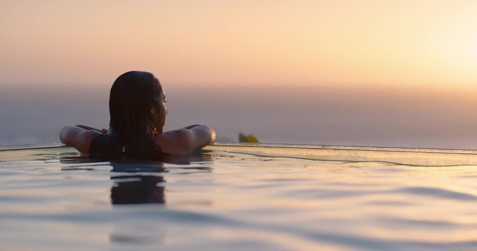 travel woman swimming in pool at luxury hotel spa with beautiful sunset view of ocean mediterranean travel holiday resort relaxing lifestyle freedom 4k