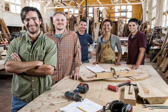 Portrait of smiling carpenters standing in workshop