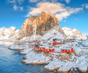 Hamnoy, Norway. Charming view of traditional wooden red rorbu (classical fishing houses on Lofotens) in Hamnoy village at spectacular mountain peak background. Hamnoy is popular tourist destination.