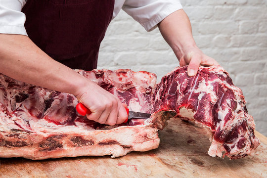 Midsection of butcher chopping beef forerib with knife