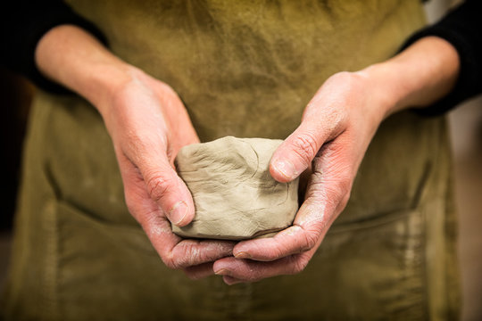 Midsection of potter holding piece of pottery clay
