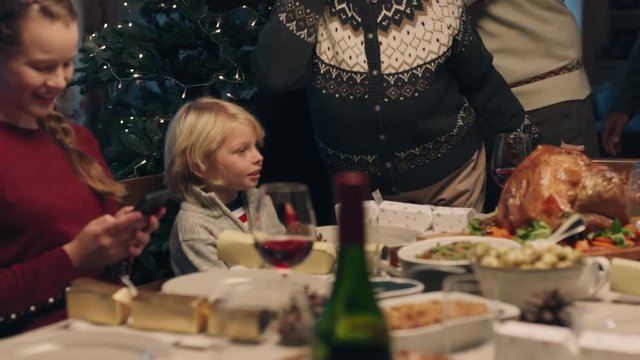 family celebrating christmas dinner with grandmother greeting grandchildren kissing girl on cheek festive holiday reunion at home 4k footage