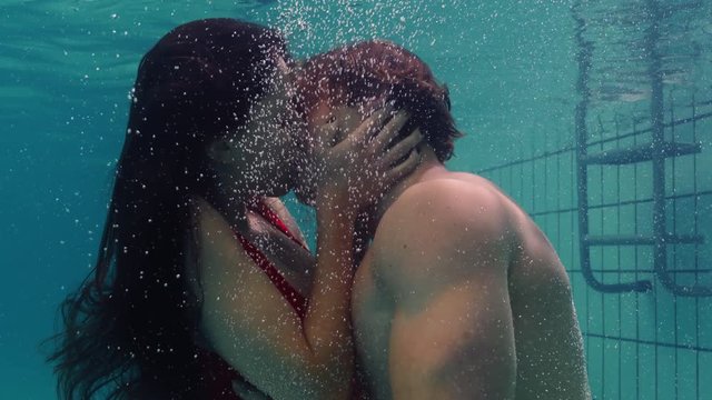 young couple kissing underwater in swimming pool enjoying intimate kiss romantic lovers submerged in water floating with bubbles in passionate intimacy 