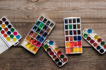top view of watercolor paint palettes on wooden brown surface
