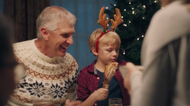 grandfather enjoying christmas dinner with grandson eating delicious homemade meal sharing holiday feast with family at home 4k footage