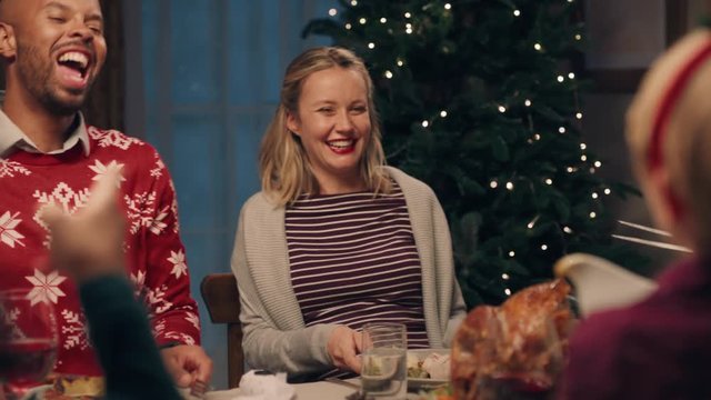 happy multiracial couple at christmas dinner with friends man enjoying celebrating festive holiday chatting sharing evening meal at home 4k