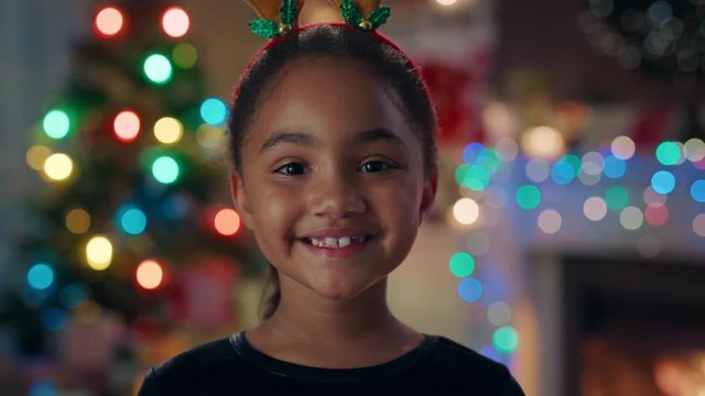 portrait cute african american girl celebrating christmas wearing funny reindeer antlers enjoying festive holiday with colorful lights having fun evening at home 4k footage 