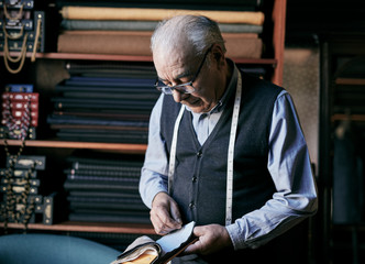 Senior tailor inspecting fabric samples