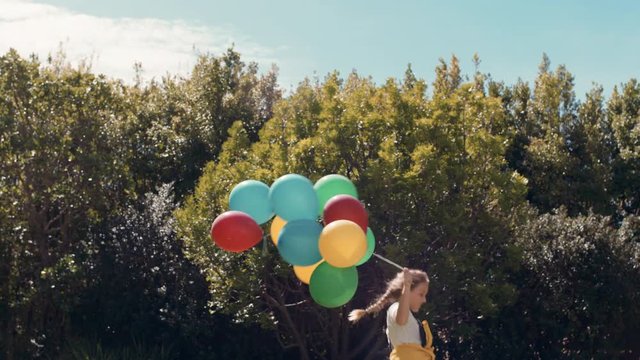 cute little girl running with balloons in park celebrating birthday party having fun summer day feeling excited playfully enjoying childhood freedom outdoors 4k