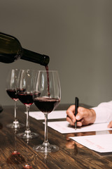 partial view of sommelier writing at table with wine glasses