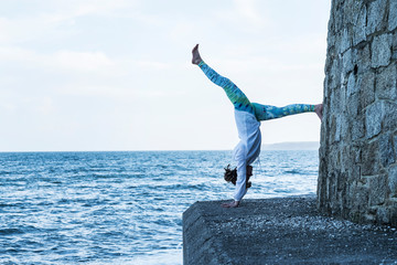 Young woman practicing handstand by ocean