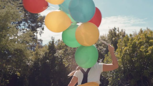 cute little girl running with balloons in park celebrating birthday party having fun summer day feeling excited playfully enjoying childhood freedom outdoors 4k