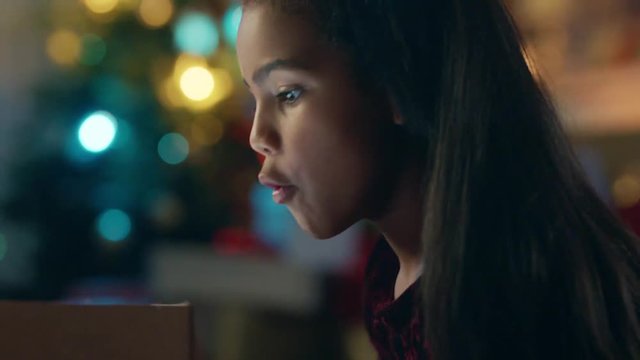 little girl unwrapping christmas present looking in box with glow on face surprised child excited for special gift having fun enjoying festive holiday celebration 4k