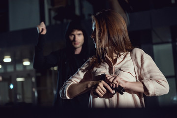 woman holding gun near thief at night