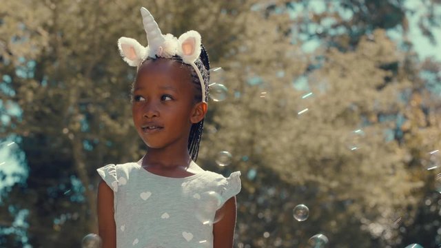 little african american girl playing with soap bubbles blowing playfully cute child having fun summer day playing bubble popping game in park 4k