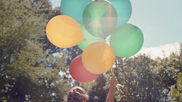 happy little girl running with balloons in park celebrating birthday party having fun summer day feeling excited playfully enjoying childhood freedom outdoors 4k