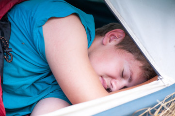 the boy is sleeping in a tent with an open entrance