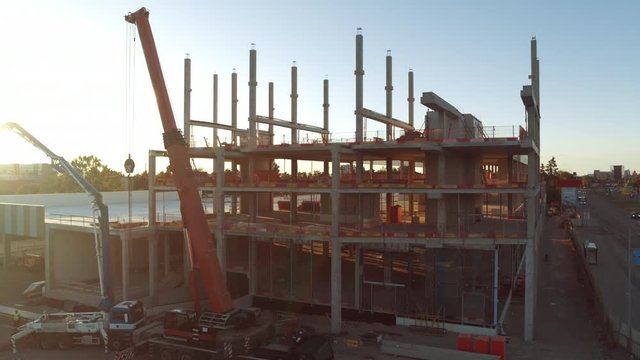 Aerial View Ascending Shot: Industrial / Commercial Property Building Construction Site. Machinery and Skyscraper Concrete Formwork Frame with in the Sunrise