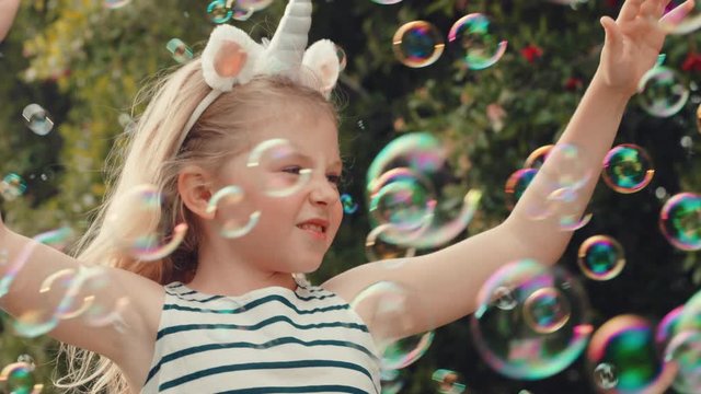 fun little girl catching soap bubbles blowing playfully cute child enjoying summer day playing bubble popping game in park 4k