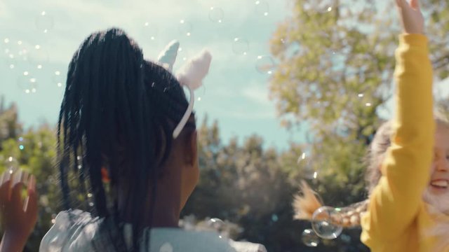 happy little girls playing with soap bubbles blowing in park children having fun summer day friends playing bubble popping game outdoors enjoying childhood freedom 4k