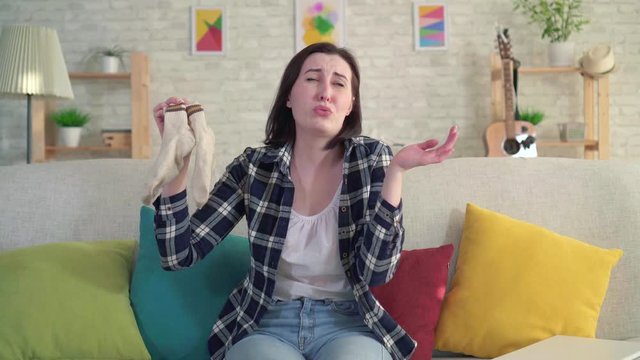 young woman holds socks in her hands and feels an unpleasant smell