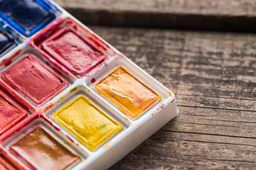 close up view of watercolor colorful paint palette on wooden table