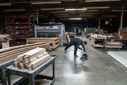 Worker cleaning floor in workshop