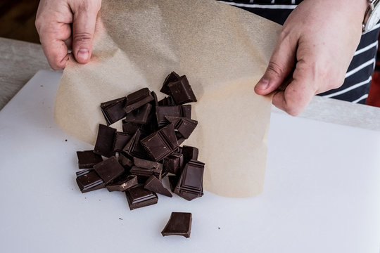 Woman's hand holding greaseproof paper and chocolate pieces