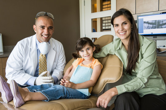Portrait of smiling dentist with patient sitting in dental clinic