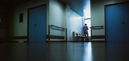 Lonely patient in full length in modern hospital waiting lobby room near the window as he waits for...