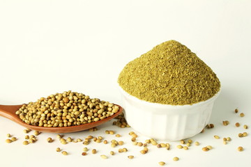 coriander powder in bowl and coriander seeds in spoon in white background top view