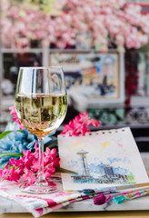 Glass of white wine at a table with art and flowers