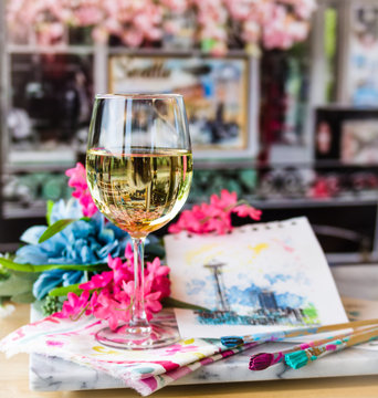 Glass of white wine at a table with art and flowers