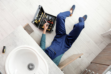 Male plumber repairing kitchen sink, above view