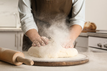 Female baker preparing bread dough at table, closeup