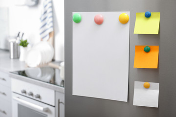 Sheets of paper with magnets on refrigerator door in kitchen. Space for text