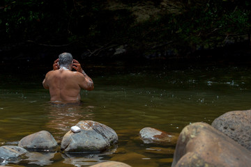 A man taking a bath in a river near the town of Togui, Boyaca, in the temperate land of the Andean mountains of Colombia.