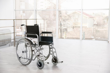 Modern wheelchair in empty room, space for text. Medical equipment