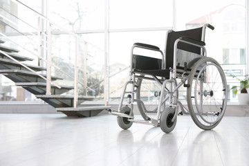 Modern wheelchair in empty room, space for text. Medical equipment