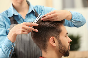 Obraz na płótnie Canvas Barber making stylish haircut with professional scissors in beauty salon