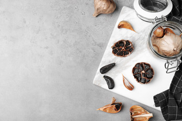 Flat lay composition with black garlic and space for text on grey table