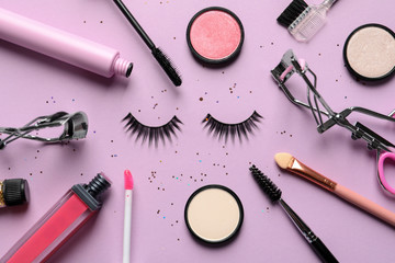 Flat lay composition with false eyelashes and other makeup products on pink background