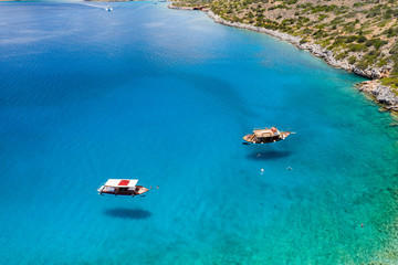 Fototapeta na wymiar Aerial view of traditional Greek boats over a crystal clear, warm ocean on the island of Crete