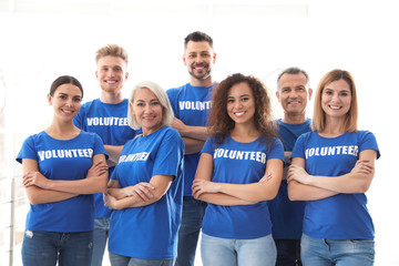 Team of volunteers in uniform on light background