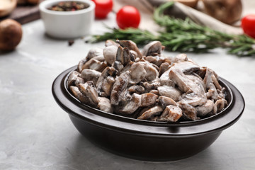 Bowl with delicious cooked mushrooms on grey table