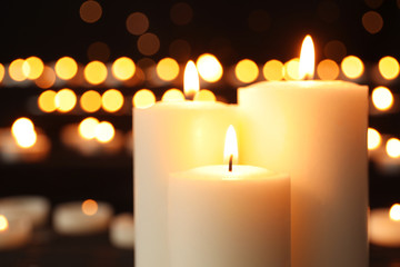 Obraz na płótnie Canvas Burning candles on dark background with blurred lights