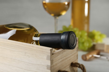 Wooden crate with bottle of wine on table, closeup