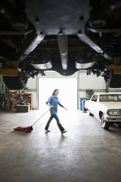 Mechanic pulling portable car jack in automobile repair shop